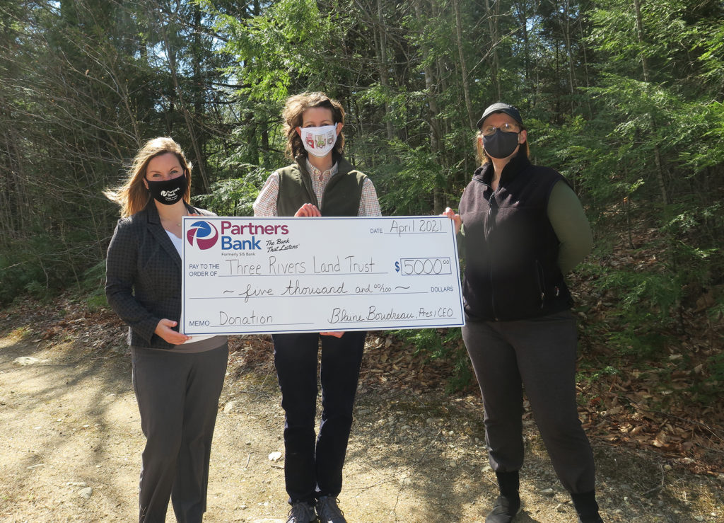Partners Bank's Cassandra Mosher presents big $5,000 check to Three Rivers Land Trust's Ruth Gutman and Cheri Brunault.