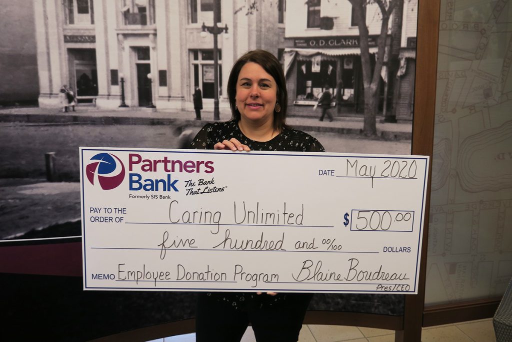 Partners Bank Assistant Branch Manager of Springvale, Kim Weaver stands with $500 check for Caring Unlimited.
