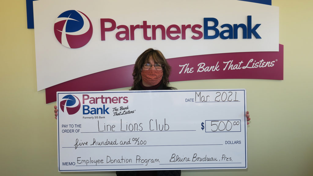 Faith Smith stands with a check for $500 for the LINE Lion's Club from the Employee Donation Program