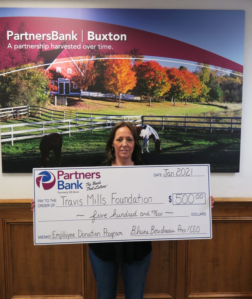 Partners Bank Senior Teller of the Buxton location, Carol Wescott, stands with a check for $500 to the Travis Mills Foundation through the bank's Employee Donation Program