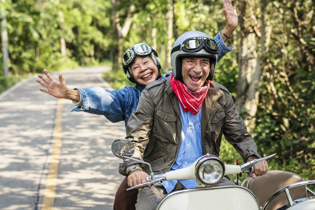 Two people riding a moped happily