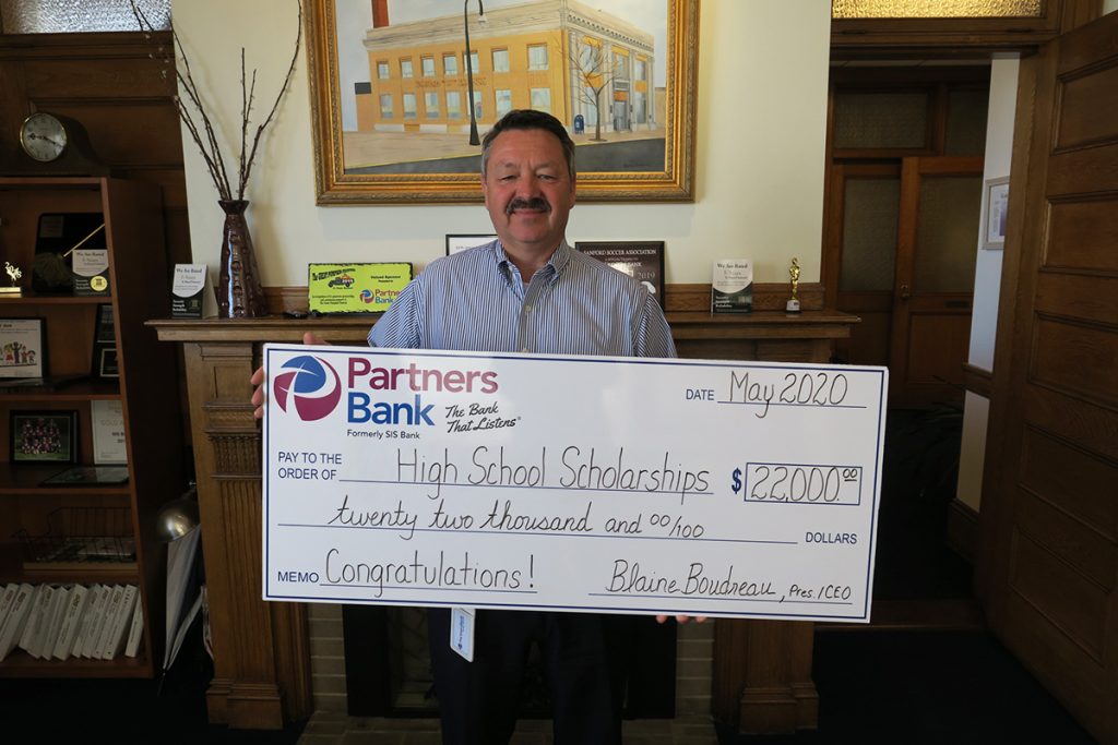 Partners Bank President and CEO poses with a check for $22,000 that will be distributed as scholarships for 20 high school seniors at the completion of the 2019-20 school year.
