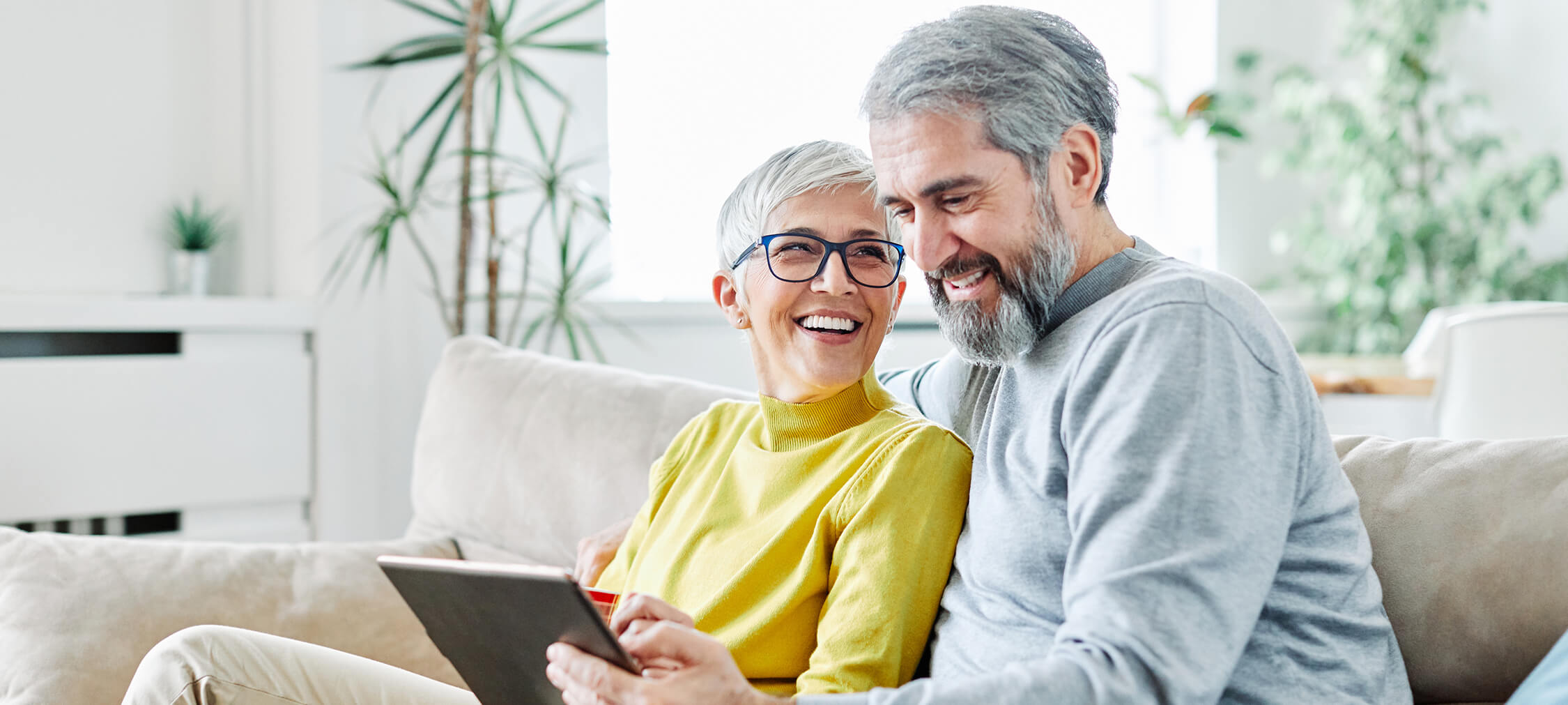 Portrait of happy smiling senior couple using tablet at home.