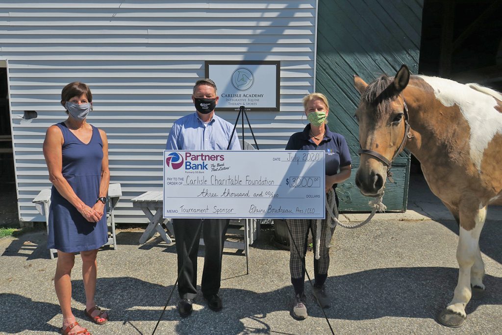Partners Bank President & CEO Blaine Boudreau (center-left) presents a $3,000 sponsorship check to Carlisle Charitable Foundation President, Diane Conley (left) and Carlisle Academy Integrative Equine Therapy & Sports Owner, Sarah Armentrout (center-right) for the Foundation’s upcoming Golf Tournament. They were also joined by farm friend, Maggie.