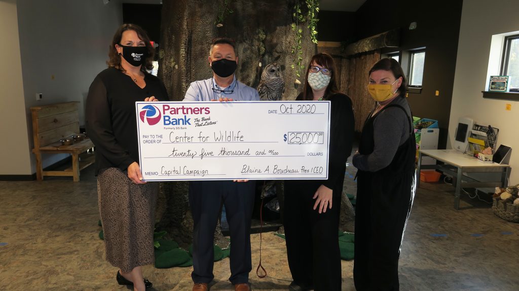 Partners Bank's Karyn Morin and Blaine Boudreau present a $25,000 check to members of the Center for Wildlife.