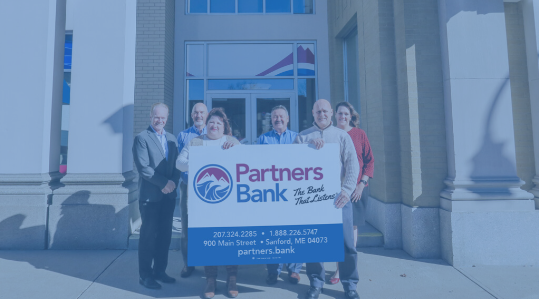 Partners Bank Team holding up new Partners Bank logo sign