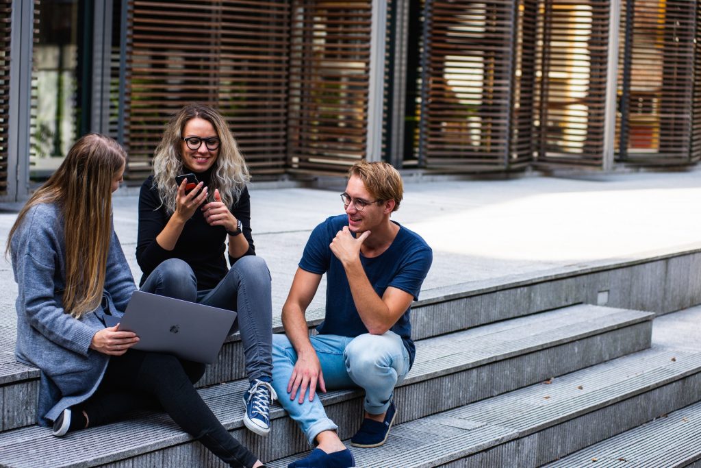 College kids sitting on steps of campus building.