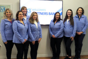 Partners Bank employees standing my screen at the Share the Power of A Wish telethon for Make A Wish Foundation